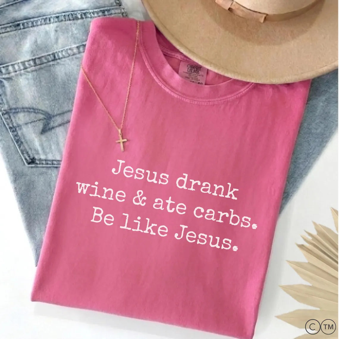 A pink t-shirt with white text that reads "Jesus drink wine & ate carbs. Be like Jesus."