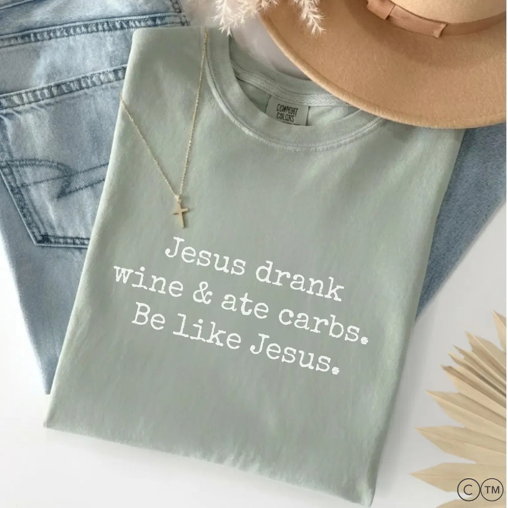 A light green t-shirt with white text that reads "Jesus drink wine & ate carbs. Be like Jesus."