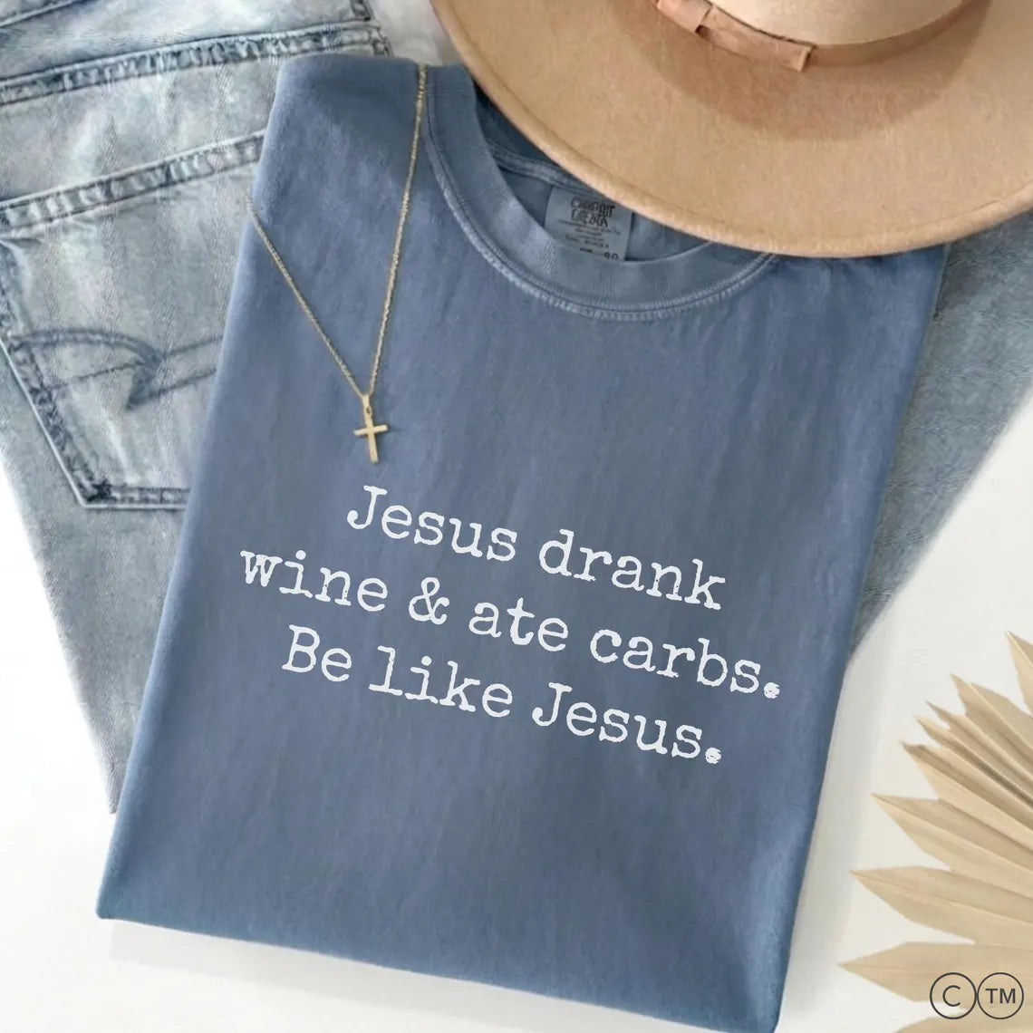 A blue t-shirt with white text that reads "Jesus drink wine & ate carbs. Be like Jesus."