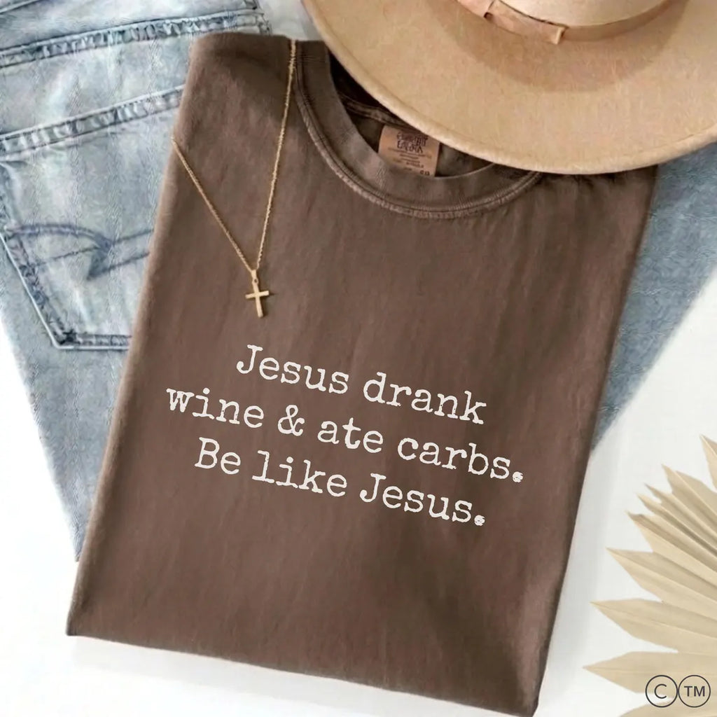 A brown t-shirt with white text that reads "Jesus drunk wine & ate carbs. Be like Jesus."